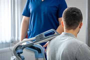 Doctor using machine to treat the patient's shoulders.