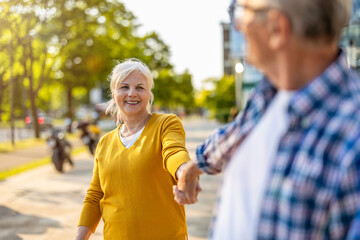 Portrait of happy senior couple standing in city street on a sunny day
