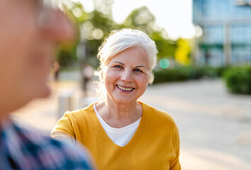 Portrait of happy senior couple standing in city street on a sunny day
