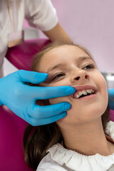 Close-up of little girl with open mouth sitting in dentist's chair.