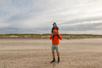 Papa und Sohn spielen im Sturm am Strand in Skagen, Dänemark