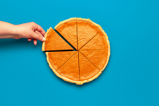 Eating pumpkin pie, above view. Woman hand taking slice of pie
