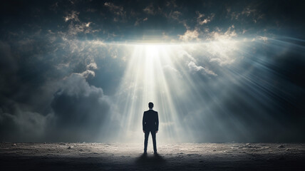 A young businessman stands facing the light of the future. - obrazy, fototapety, plakaty