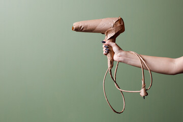 Female hand holds a brand new hair dryer wrapped in rustic beige craft paper. Black Friday concept.