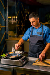 A close-up of a chef frying a beef patty for a burger in the professional kitchen of an Italian restaurant