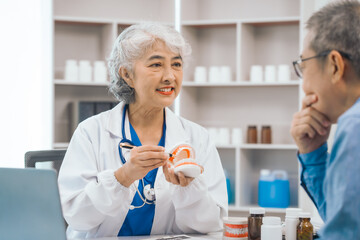 Asian people mature dentist having a compassionate conversation with elderly patient, discussing...