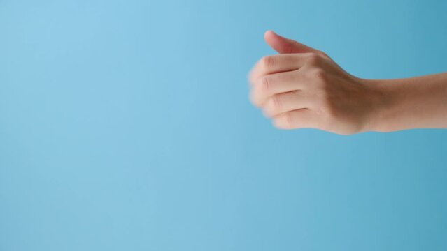 Vertical video of female hand pointing on you and Come closer isolated on blue studio background with copy space for advertisement. Body language concept. With place for text or promotional content