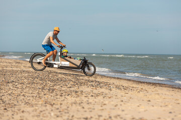 Fototapeta premium Papa und Kind haben Spaß mit dem Lastenrad am Strand,Skagen,Dänemark