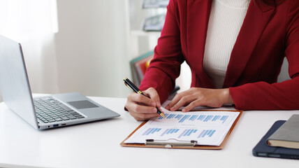 Asian businesswoman talking on the phone and smiling at home and working at table, laptop and coffee cup