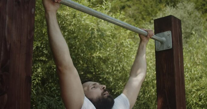 Portrait of young man while doing pull-ups exercise in slow-motion.