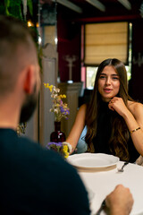 Young couple guy and girl sitting in an Italian restaurant and chatting sweetly while on a date 