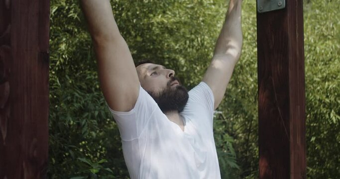 Bearded young man doing pull-ups exercise in slow-motion.