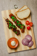 Barbecue on skewers on a cutting board serving dishes top view