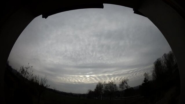 Cloudy grey sky with moving clouds Fluctus and sun - view from the window with horizon with trees and traffic cars on DK1 national road in Poland - timelapse, panorama 160.