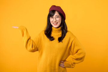 Happy female painting, 30s Asian beautiful young woman artist holding hip and pointing palm hand to free copy space, studio shot isolated on yellow background, Paintings and art advertising concept. - obrazy, fototapety, plakaty