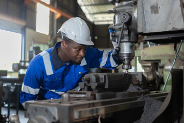 Male African American workers wearing uniform safety and hardhat working an iron cutting machine in factory Industrial. Engineering worker man work machine lathe metal. Heavy industry concept.