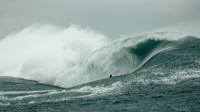 surfer on big wave in stormy seas