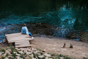 A girl is sitting on the shore of a blue lake. Beautiful natural background. Blue Lake in Kazan....