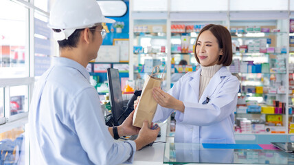 asian thai engineer construction worker customer buy Medication and pharmacist give recycle paper bag at Pharmacy medical shop and drugstore medication. Pharma Store Health Care Products