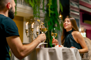 Young couple guy and girl sitting in an Italian restaurant sweetly chatting and drinking wine while...