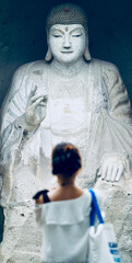 A female tourist earnestly praying to a Buddha statue.