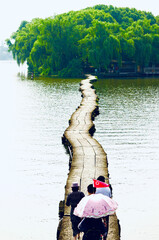 Tourists walking on a floating path on the lake, heading towards a small island on the other side