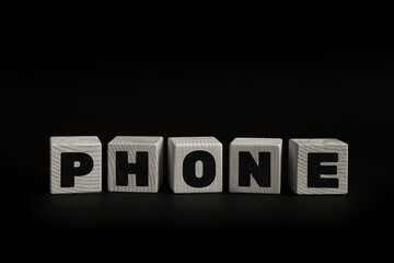 Word PHONE written with wooden cubes. Studio shot of some arranged wooden blocks with a textual message.