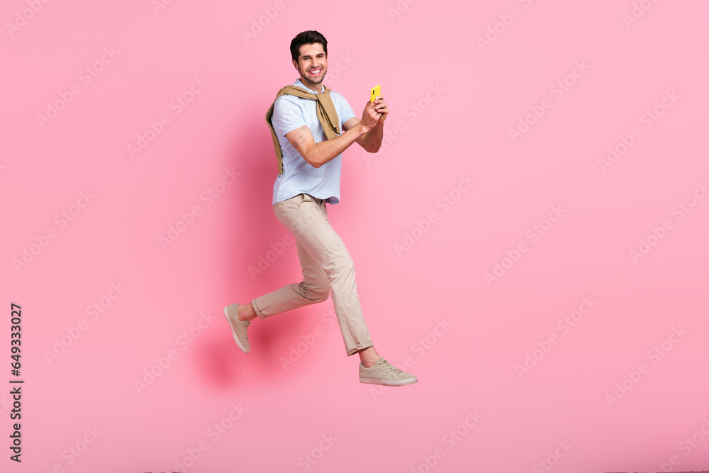 Poster full size profile portrait of excited person jumping rush empty space use smart phone isolated on pi
