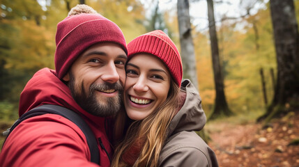 Fototapeta premium stockphotography, copy space, Attractive couple taking a selfie in a forest in autumn. Outdoors activity. Young couple walking outdoors, exploring nature. Autumn walk.