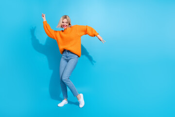 Full length photo of overjoyed cute girlish woman dressed knitwear sweater jeans dancing show v-sign isolated on blue color background