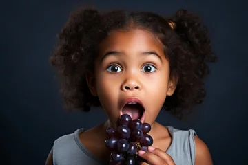 Foto op Canvas black girl eating grapes on a dark background © vasyan_23