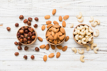Assortment of nuts in wooden bowl on colored table. Cashew, hazelnuts, walnuts, almonds. Mix of nuts Top view with copy space