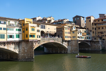 Fototapeta na wymiar view of Arno river with tourist boat and ponte vecciho old bridge