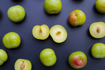 Fresh green plum fruit on dark background.