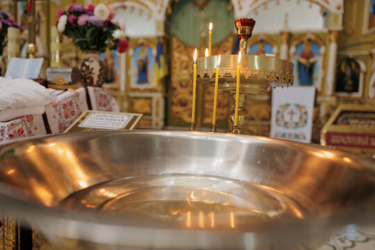 Baptismal font with blessing water and wax candles for Newborns baptism rite in Orthodox church.
