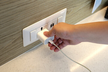 Hand insert a plug of the phone charger into socket. - obrazy, fototapety, plakaty