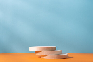 Wooden cylindrical podiums on an orange and blue background. Podium, presentation display with copy...