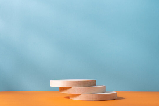 Wooden Cylindrical Podiums On An Orange And Blue Background. Podium, Presentation Display With Copy Space