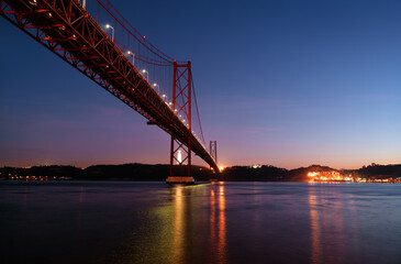 Beautiful landscape with suspension 25 April bridge over the Tagus river in Lisbon at night time, Portugal.