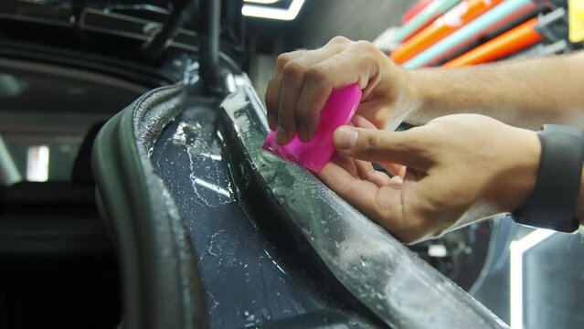 Process of applying a protective PPF film to a car.Closeup shot of Hands of a professional applying a protective film of laminate. 