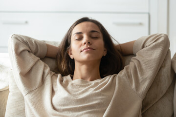 Close up peaceful calm woman leaning back on cozy couch, relaxing with closed eyes, napping or daydreaming, mindful beautiful girl stretching on sofa, sleeping or meditating, stress relief