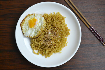 top view of plate of noodle with egg and chopstick, isolated on textured background. flat lay photo concept