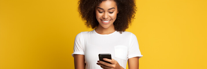 Latin woman wearing a white t-shirt and holding mobile phone looking at smartphone isolated on yellow background - obrazy, fototapety, plakaty