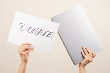 Donation technology to charity. Volunteer hands holding laptop computer and paper board with word Donate