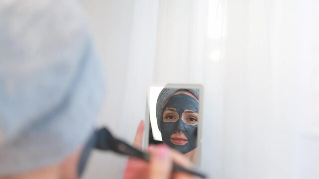 Woman with a cleansing face mask based on clay and activated carbon.