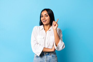 Excited indian woman raising finger up having idea, blue background