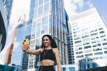 Smiling sporty woman with smartphone taking selfie