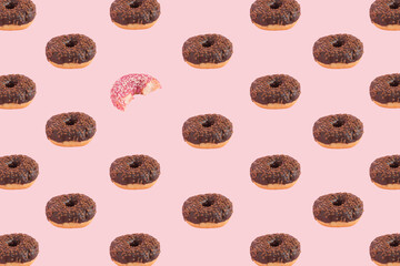 Chocolate donuts and half eaten strawberry doughnut on a pink pastel background. Pattern concept. Creative sweet arrangement.