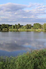 Scenery landscape with lake, trees and cloudy sky.