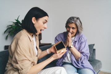 Surprised woman opening gift received from loving mother